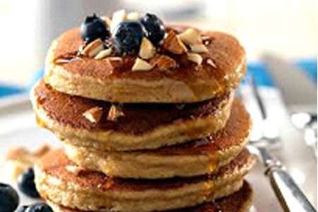Fluffy vegan buckwheat pancakes topped with maple syrup and fresh berries