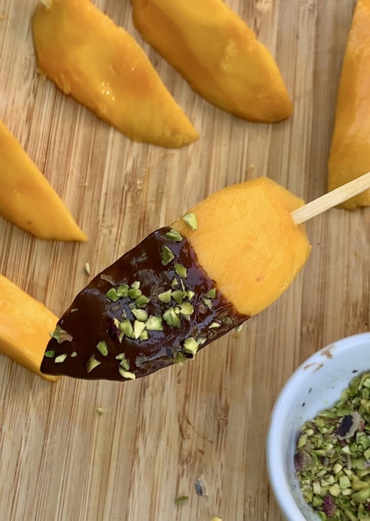 Adding topping to chocolate mangoes